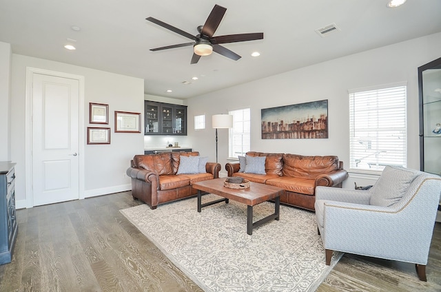 living room with ceiling fan, wood-type flooring, and bar area