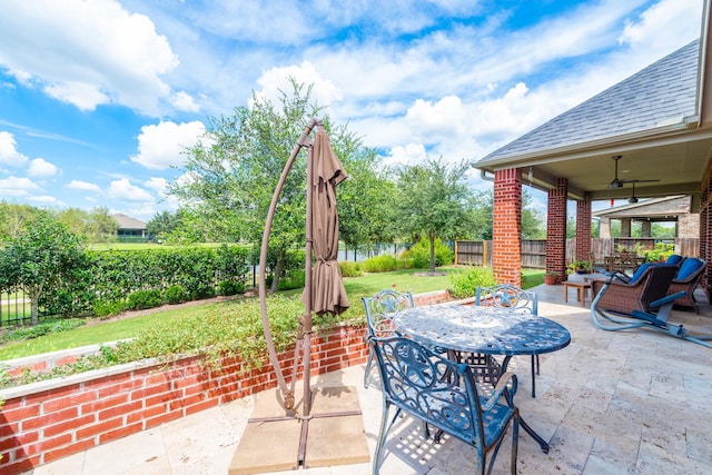 view of patio featuring outdoor dining space, a fenced backyard, and a ceiling fan