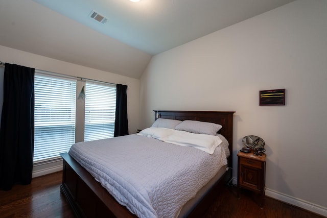 bedroom featuring dark hardwood / wood-style flooring, vaulted ceiling, and multiple windows