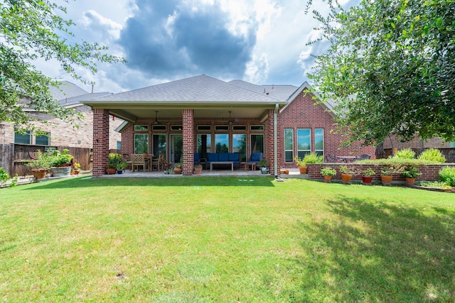 back of property with ceiling fan, a patio area, an outdoor living space, and a yard