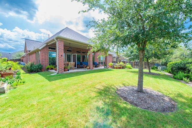rear view of property with brick siding, fence, a yard, and a patio