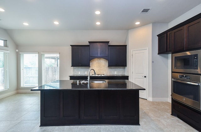 kitchen featuring visible vents, baseboards, stainless steel oven, decorative backsplash, and built in microwave