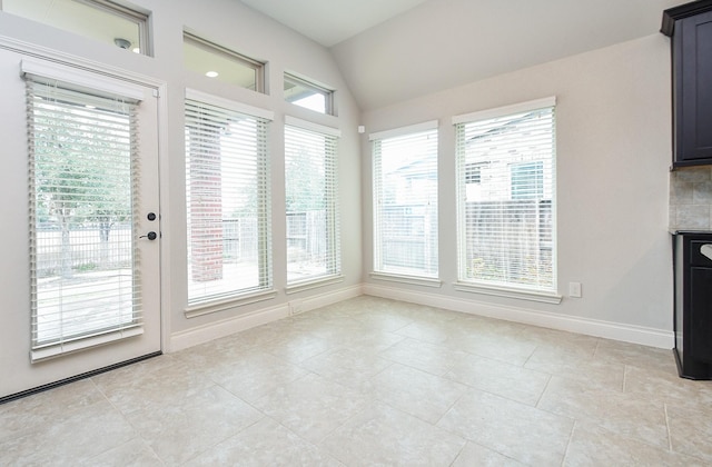 interior space with light tile patterned floors, baseboards, and vaulted ceiling