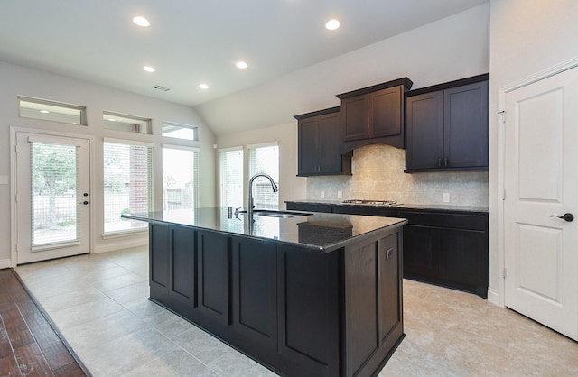 kitchen with lofted ceiling, sink, an island with sink, decorative backsplash, and stainless steel gas stovetop