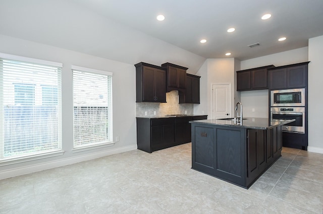 kitchen featuring tasteful backsplash, sink, a center island with sink, and appliances with stainless steel finishes