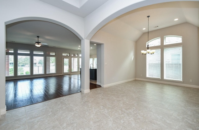 spare room featuring recessed lighting, plenty of natural light, lofted ceiling, and ceiling fan with notable chandelier