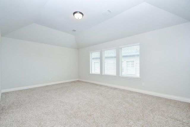 unfurnished room with visible vents, baseboards, lofted ceiling, and carpet