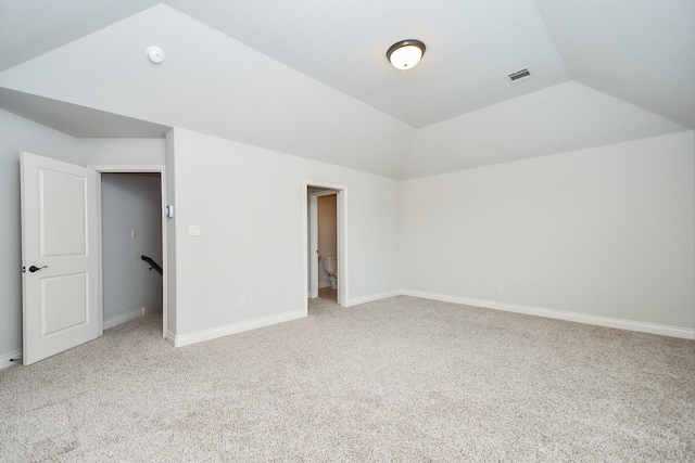 interior space with vaulted ceiling and light colored carpet