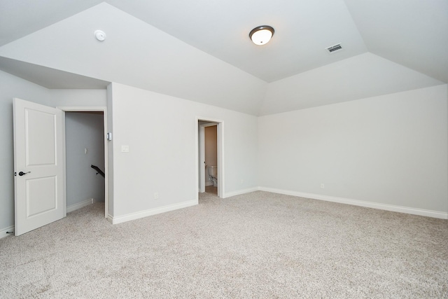 unfurnished bedroom featuring light carpet, visible vents, baseboards, and lofted ceiling