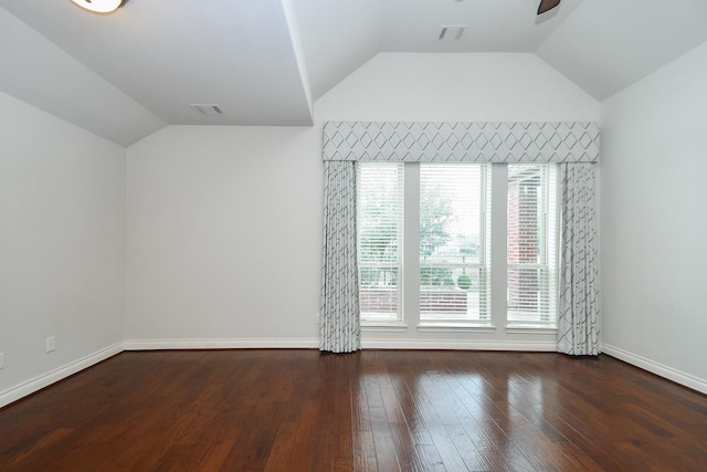 empty room featuring visible vents, baseboards, hardwood / wood-style floors, and vaulted ceiling
