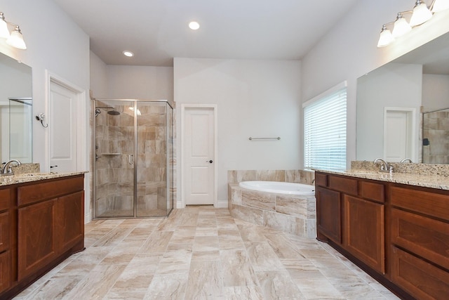 bathroom featuring a shower stall, a garden tub, two vanities, and a sink