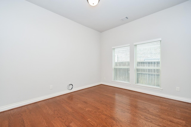 spare room featuring visible vents, baseboards, vaulted ceiling, and wood finished floors