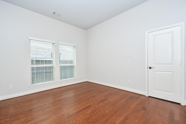 spare room featuring dark wood-type flooring, baseboards, and visible vents