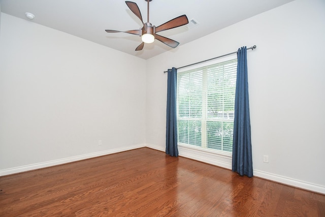 unfurnished room with wood finished floors, baseboards, and a ceiling fan