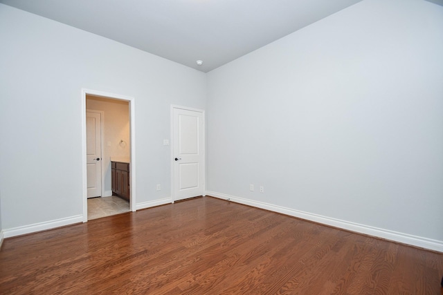 spare room featuring dark wood-type flooring and baseboards