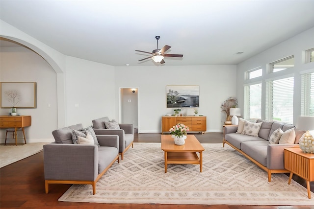 living area with visible vents, baseboards, arched walkways, a ceiling fan, and wood finished floors