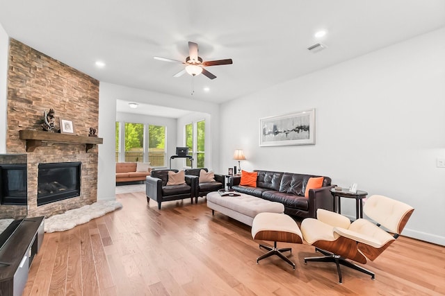 living room featuring a fireplace, light hardwood / wood-style floors, and ceiling fan