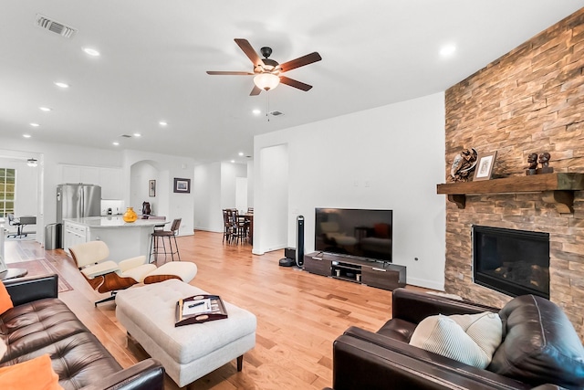 living room with ceiling fan, a fireplace, and light hardwood / wood-style flooring