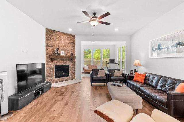 living room featuring ceiling fan, light hardwood / wood-style floors, and a fireplace