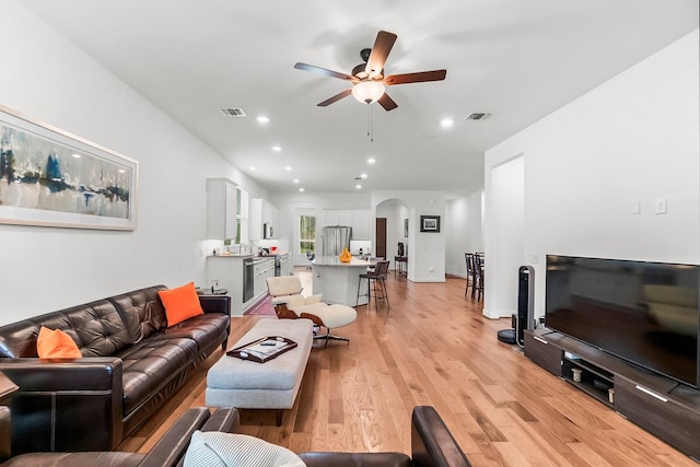 living room with light wood-type flooring and ceiling fan