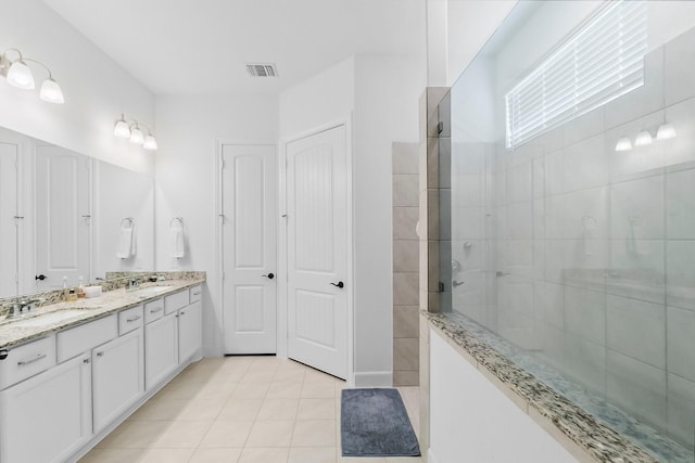 bathroom with tile patterned flooring, vanity, and walk in shower