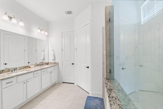 bathroom featuring tile patterned flooring, vanity, and a shower