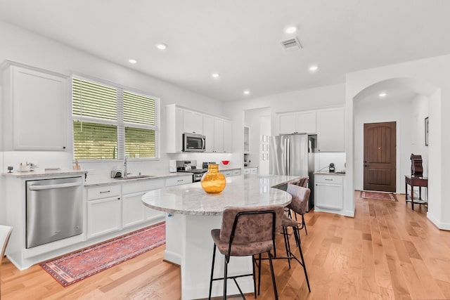 kitchen featuring sink, stainless steel appliances, a kitchen island, a kitchen bar, and white cabinets