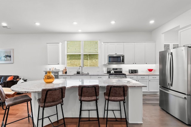 kitchen with a center island, white cabinetry, a breakfast bar area, and appliances with stainless steel finishes