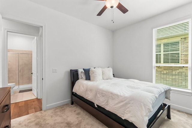 bedroom with multiple windows, ensuite bathroom, and ceiling fan