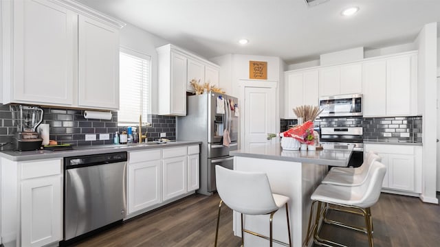 kitchen featuring tasteful backsplash, a kitchen island, dark hardwood / wood-style flooring, white cabinetry, and stainless steel appliances