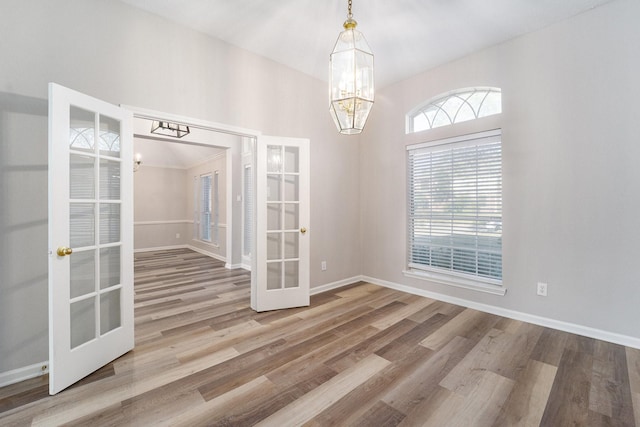 empty room featuring hardwood / wood-style floors, an inviting chandelier, and french doors