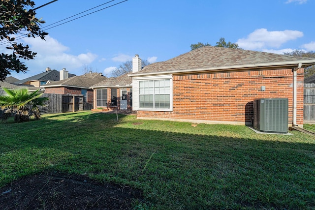 back of property with a lawn and central AC