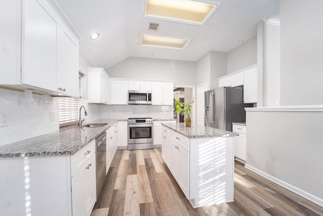 kitchen with a center island, stainless steel appliances, white cabinetry, and sink