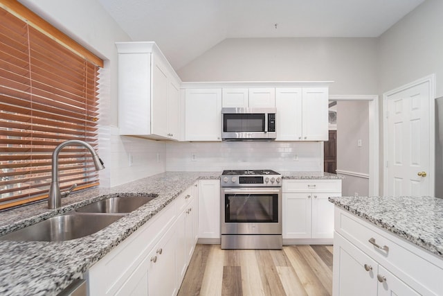 kitchen featuring decorative backsplash, appliances with stainless steel finishes, sink, white cabinets, and light hardwood / wood-style floors