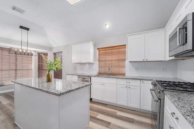 kitchen with lofted ceiling, sink, a kitchen island, white cabinetry, and stainless steel appliances