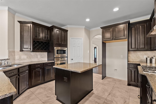 kitchen with light stone counters, sink, a center island, and appliances with stainless steel finishes