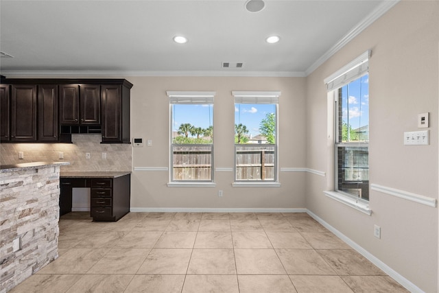 kitchen with tasteful backsplash, crown molding, and dark brown cabinets