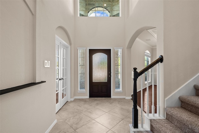 tiled foyer entrance with a high ceiling, ornamental molding, and plenty of natural light