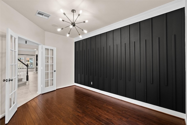 unfurnished room featuring french doors, a notable chandelier, and hardwood / wood-style flooring