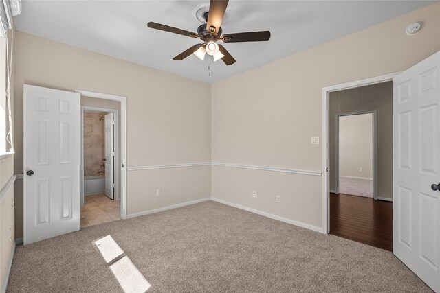 unfurnished bedroom featuring light carpet, connected bathroom, and ceiling fan