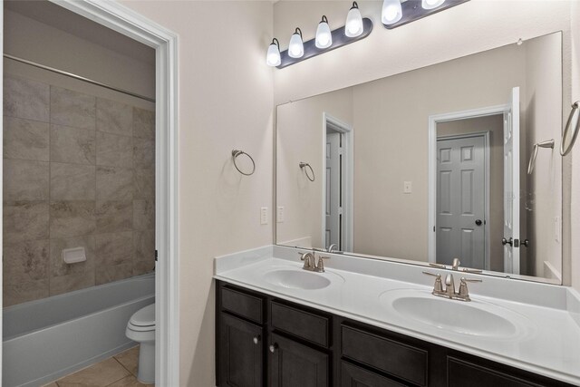 full bathroom with tile patterned flooring, vanity, tiled shower / bath, and toilet