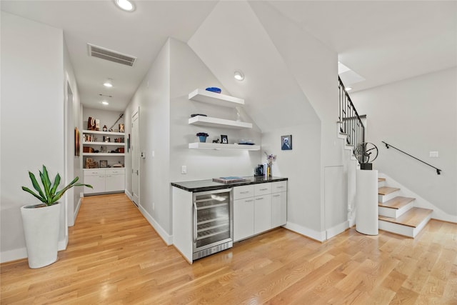 bar with wine cooler, vaulted ceiling, and light hardwood / wood-style floors