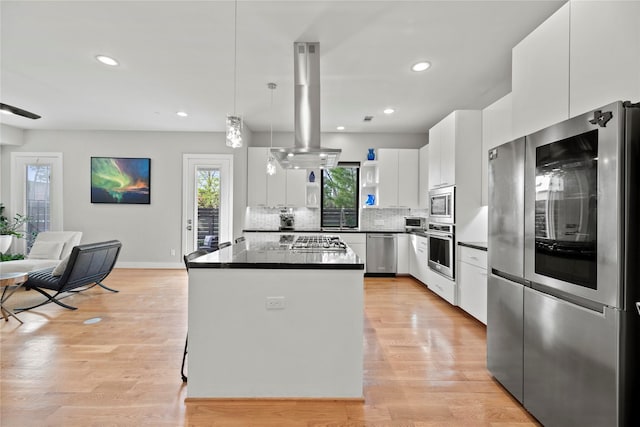 kitchen featuring white cabinets, a kitchen island, decorative light fixtures, stainless steel appliances, and island range hood