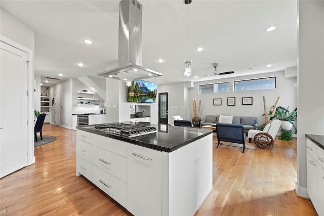 kitchen with white cabinetry, island range hood, stainless steel gas cooktop, and hanging light fixtures