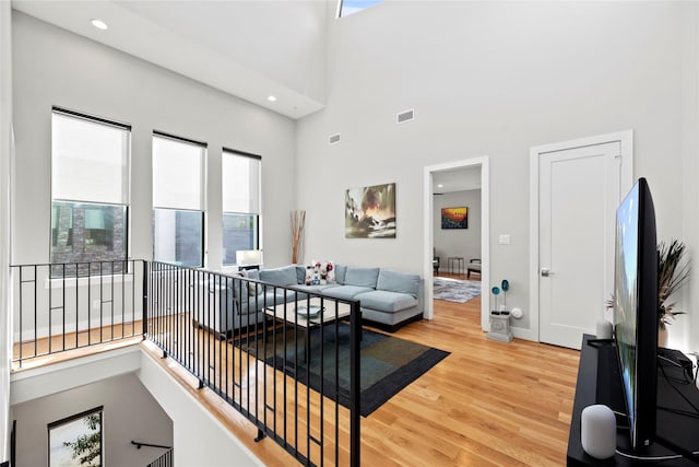 living room featuring wood-type flooring, a high ceiling, and a wealth of natural light