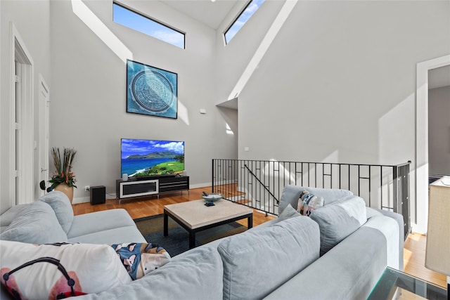 living room featuring a skylight, a towering ceiling, and hardwood / wood-style floors