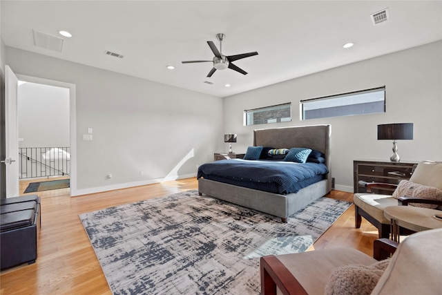 bedroom featuring ceiling fan, hardwood / wood-style floors, and multiple windows