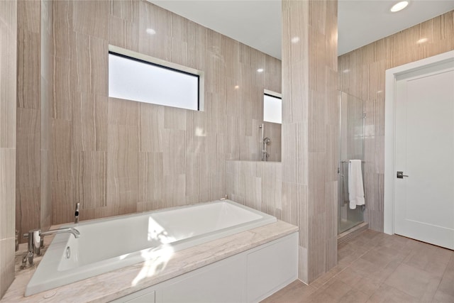 bathroom with tile walls and independent shower and bath