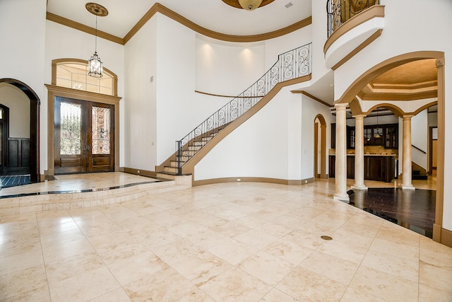 entryway with a towering ceiling, crown molding, and french doors