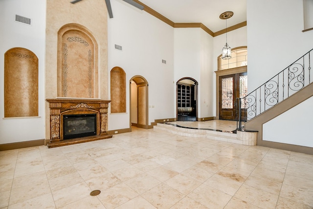 entrance foyer featuring a high end fireplace, a towering ceiling, and ornamental molding